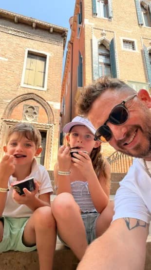A father and two children eating gelato on steps in Italy