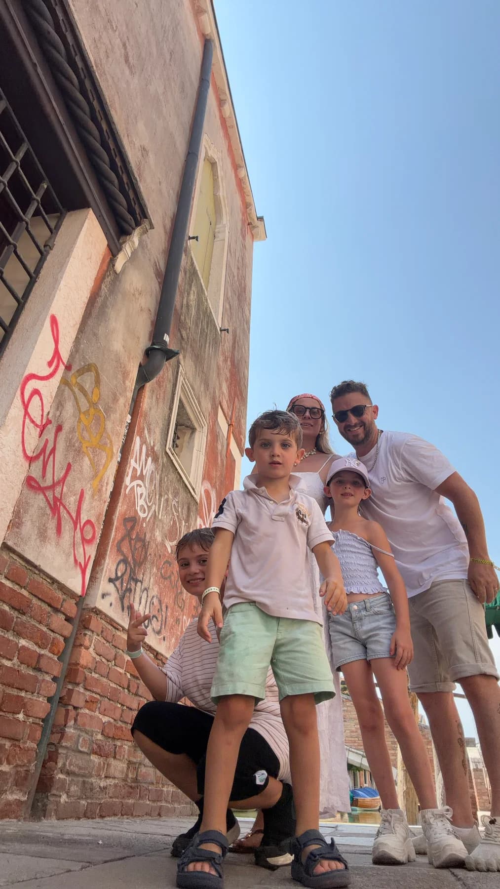 A family of five together in a sunlit Italian alley