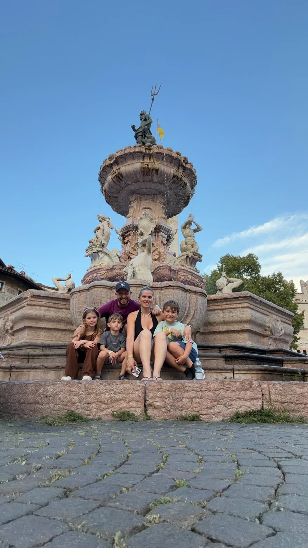 A family of five sitting together in front of an Italian fountain